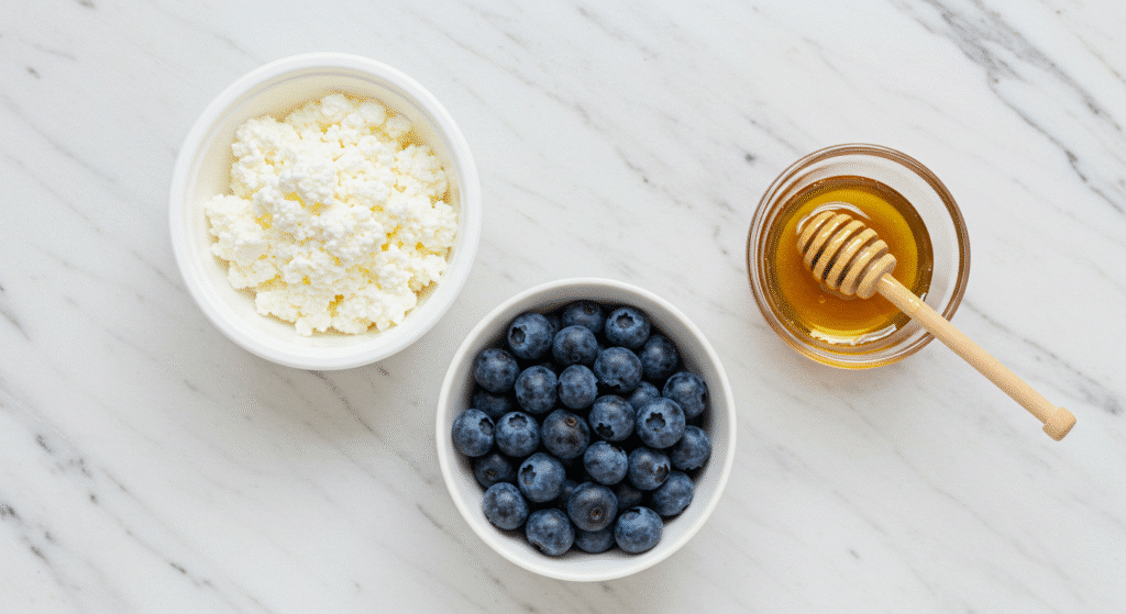 Three ingredients for cottage cheese ice cream: cottage cheese, blueberries, and honey