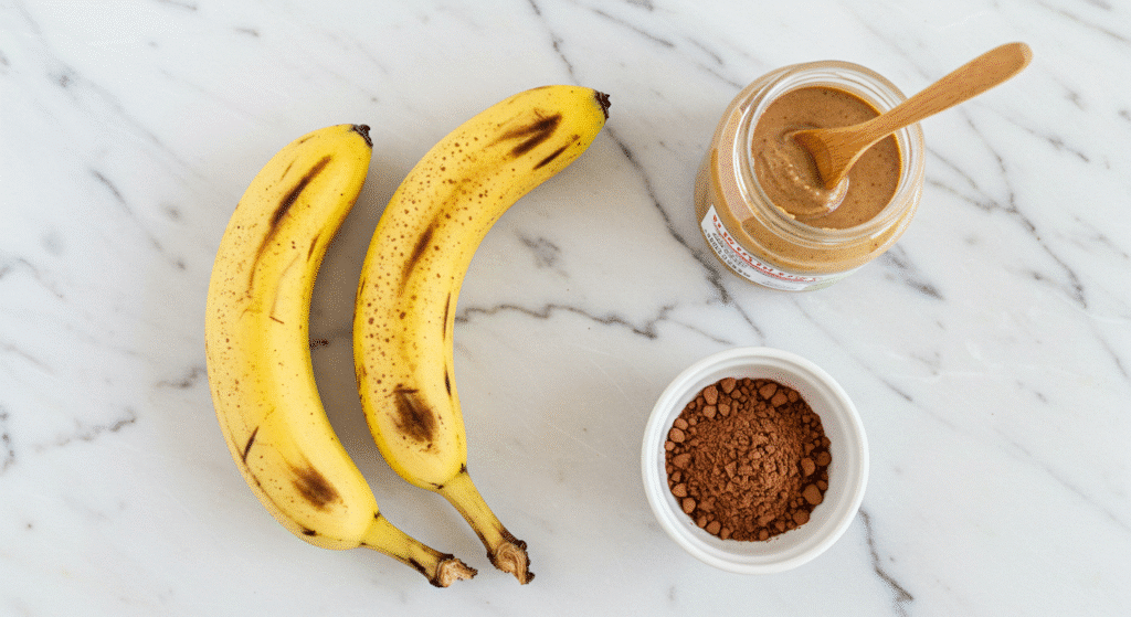 Three ingredients for healthy brownies - ripe bananas, almond butter jar, and cocoa powder